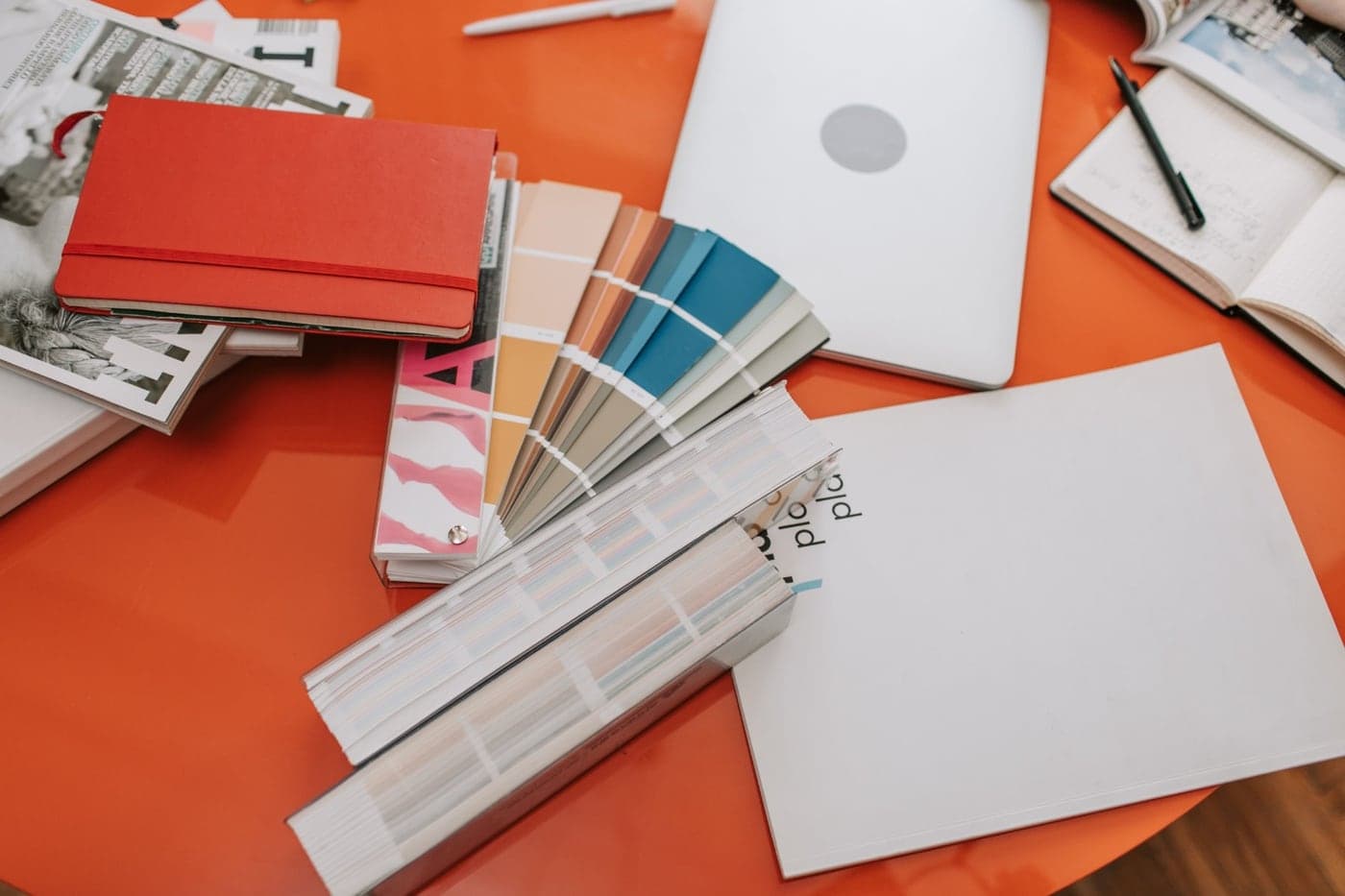 Colour swatch fans and brand materials on an orange surface